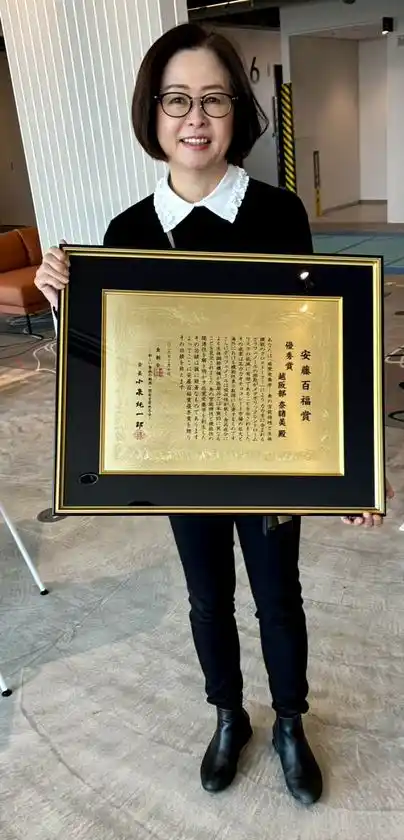 賞状を掲げる越阪部 奈緒美教授